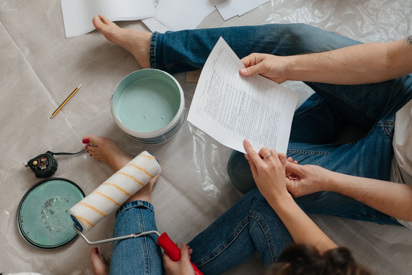 Deux artisans comparant des devis papier autour d'une table, avec une calculatrice et un plan de rénovation