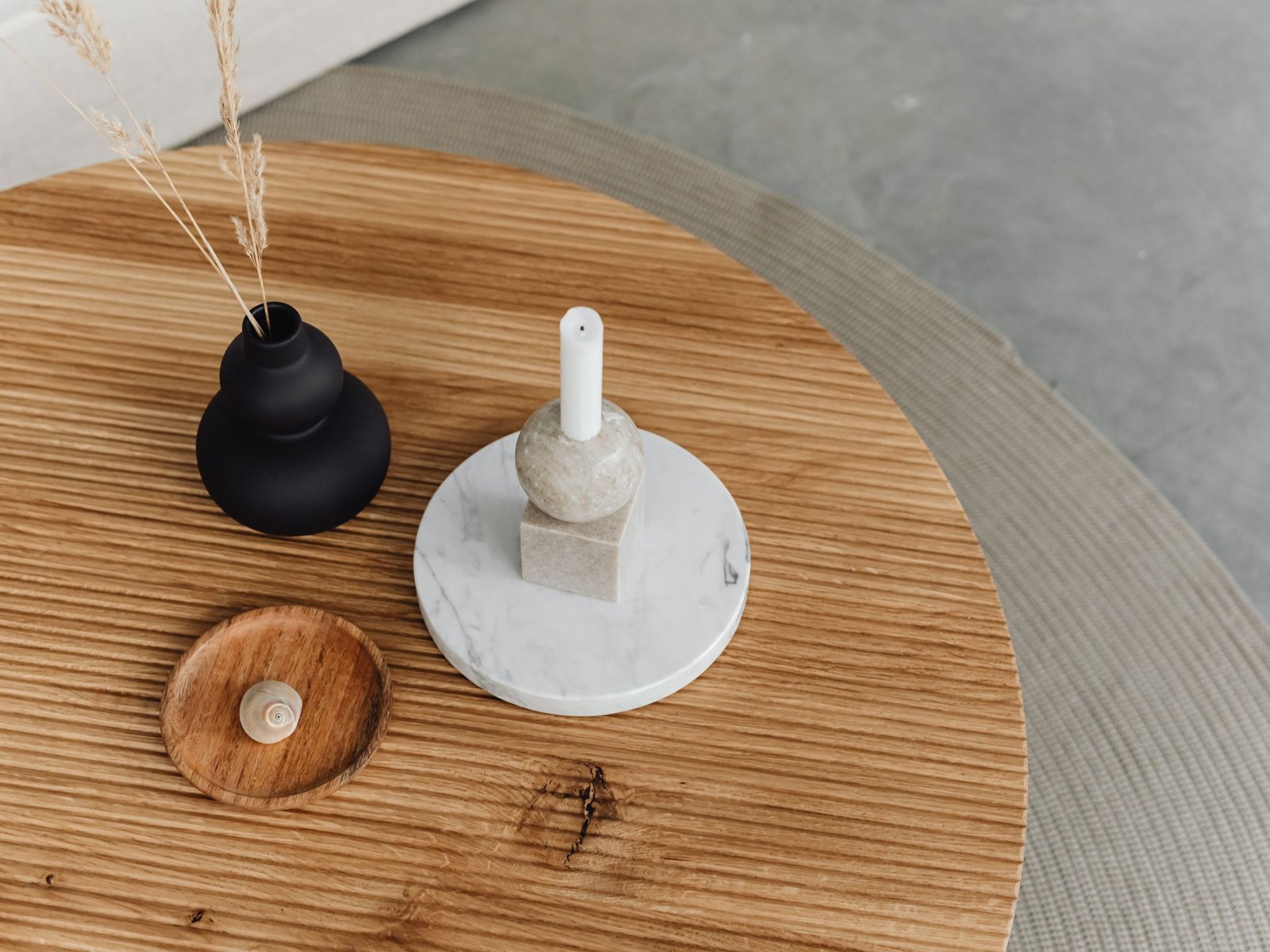 Table basse travertin ovale dans un salon lumineux, plateau en pierre naturelle beige et pieds en métal noir